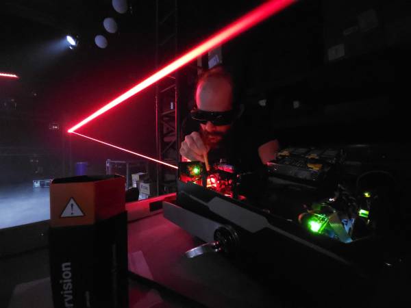 a technician looking at the inside of a laser, with safety goggles